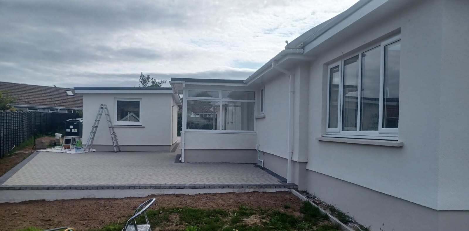 A newly rendered bungalow, finished flat and smooth, with a garden room extension in the same render